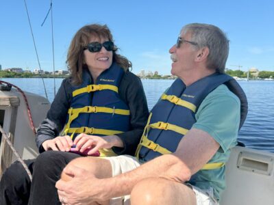 Sailor, Tom, sitting in a sailboat next to his wife, Cheryl. They're smiling at each other.