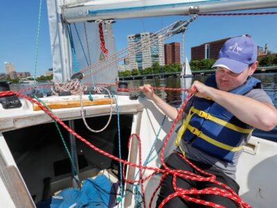Sailor, Tim Vernon, pulling on a rope (jib sheet) while sailing